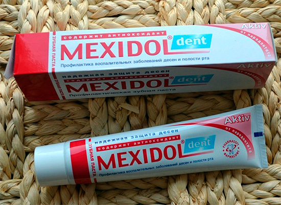 Imaginea prezintă ambalajul și un tub din pasta de dinți Mexidol Dent Active.